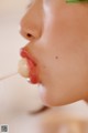 A close up of a woman with a toothpick in her mouth.