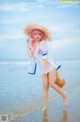 A woman in a straw hat is walking on the beach.