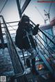 A woman standing on top of a metal stairway.