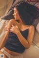 A woman laying on a bed in a black top and white panties.