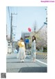 Two young women walking down a street holding balloons.