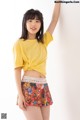 A young woman wearing a yellow shirt and a colorful skirt.