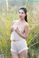 A woman in a white lingerie posing in a field.