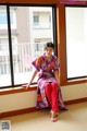 A woman in a purple kimono sitting on a window sill.