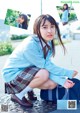 A young woman in a school uniform crouching on the ground.