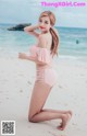 A woman in a pink bikini posing on the beach.