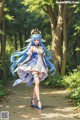 A woman with long blue hair walking down a path in the woods.