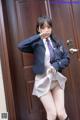 A woman in a school uniform posing in front of a door.