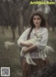 A woman holding a baby goat in a field.