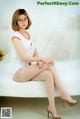 A woman sitting on top of a white bed wearing glasses.