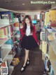 A woman standing in front of a book shelf filled with books.