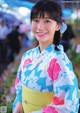 A woman in a blue and pink kimono smiles at the camera.