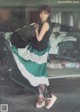 A woman in a green and white dress standing in front of a car.