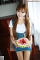 A woman sitting on a chair holding a slice of watermelon.