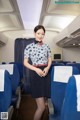 A woman standing in the aisle of an airplane.